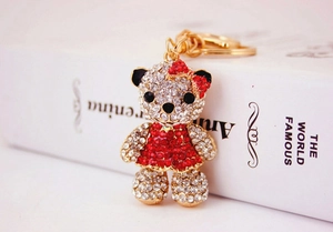 Close-up of crystal-encrusted teddy bear keychain with red bow and gold metal ring