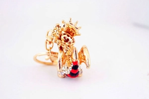Détails d'un porte-clés dragon doré avec émail rouge et strass brillants sur métal