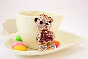 Detailed close-up of a sparkling crystal bear keychain featuring purple rhinestone dress