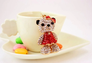 Detailed view of a crystal bear charm with red rhinestones hanging on a white coffee cup