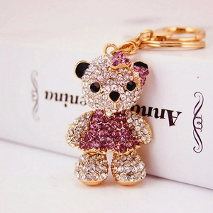 Sparkling crystal teddy bear keychain with purple rhinestones on a white book background