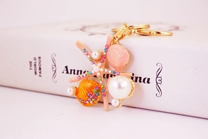 Détail d'un porte-clés marin avec étoile de mer rose, strass colorés et perles blanches
