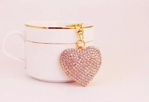 Close-up of pink crystal heart keychain hanging on a white ceramic mug rim
