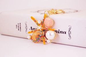 Détail macro du porte-clés étoile de mer avec émail orange, cristaux colorés et perles