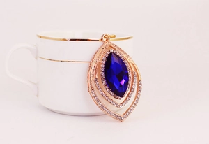 Detailed macro view of leaf shaped pendant with blue gemstone and rose gold finish