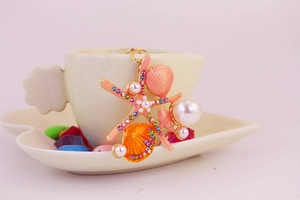 Vue détaillée du porte-clés étoile de mer avec perles et strass sur une tasse blanche