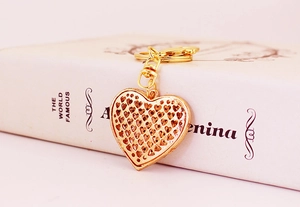 Detailed close-up of a hollow-carved golden heart keychain with a premium metallic finish