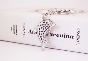Macro shot of silver dolphin keychain with crystal rhinestones on a white book