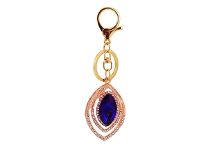 Macro detail of vintage gold peacock feather keychain with blue gemstone and white zircon