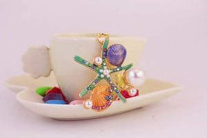 Détail du pendentif étoile de mer et coquillage avec strass colorés sur une tasse