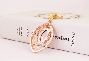 Detail view showing the textured rose gold metal back of the hollow peacock feather keychain