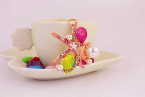 Détail de breloques étoile de mer et coquillage avec perles et cristaux sur une tasse