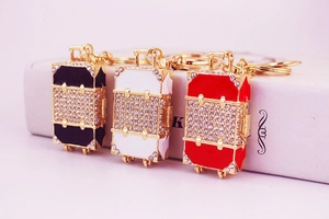 Macro shot of three luxury suitcase keychains with crystals and gold lobster clasps