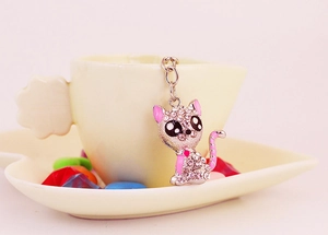 Sparkling kitten keychain with pink enamel details and crystals on a coffee cup
