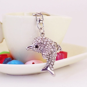 Sparkling dolphin keychain with clear crystals and silver lobster clasp on a white cup
