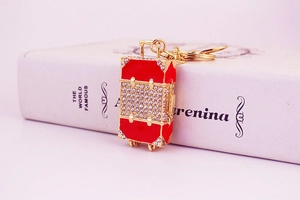 Detail of red suitcase keychain with sparkling rhinestones and golden metal hardware