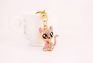 Detailed close-up of a cute sitting cat keychain with pink rhinestones on a white cup