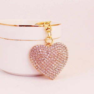 Sparkling pink rhinestone heart keychain with gold finish on a decorative cup