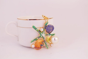Détail d'un porte-clés étoile de mer coloré avec perles posé sur une tasse blanche
