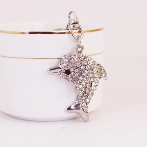 Sparkling crystal dolphin keychain accessory with white rhinestones on a white porcelain cup