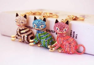 Vue détaillée de trois porte-clés chat avec des strass colorés en plaqué or brillant