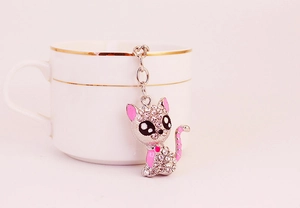 Close-up of white rhinestone-encrusted sitting cat keychain with pink enamel accents