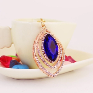 Peacock feather style pendant featuring a deep blue marquise gem in rose gold framing