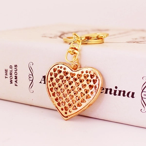 Golden heart-shaped keychain with intricate hollow patterns leaning against a white book