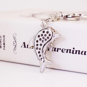 Elegant dolphin shaped silver metal keychain with sparkling crystal inlay on a book