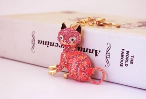 Détail du porte-clés chat en strass rose avec base en métal doré posé sur un livre