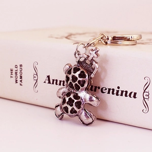Vintage silver alloy crown bear keychain accessory placed on an antique book