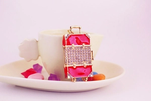 Detail of red enamel suitcase keychain with sparkling rhinestones and gold-tone metal frame