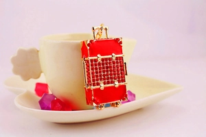 Macro shot of red rhinestone suitcase keychain with golden metal edges as a bag charm