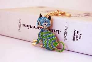 Gros plan d'un porte-clés chat doré avec strass bleus et émail posé sur un livre