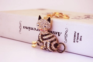 Gros plan d'un porte-clés chat porte-bonheur doré orné de strass brillants et d'émail noir