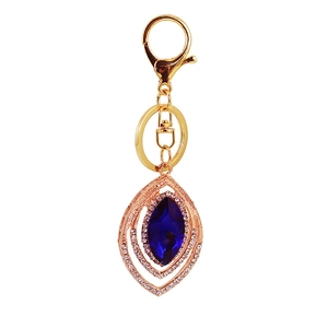 Peacock feather vintage keychain with blue crystal and gold plating on white background