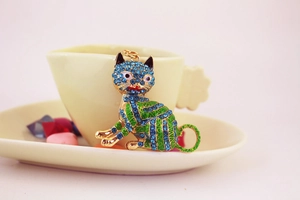 Détail du porte-clés chat porte-bonheur avec strass bleus et émail vert sur métal