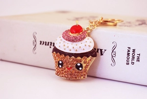 Close-up of sparkling crystal cupcake keychain with cute smiley face and pink rhinestones