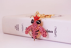 Dettaglio ravvicinato di un portachiavi a forma di ape dorata con strass rosa e corona