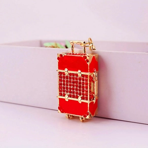 Red rhinestone suitcase keychain with gold metal frame and decorative wheels