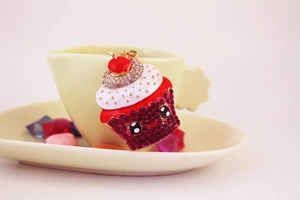 Close-up of a cupcake keychain featuring pink rhinestones and a cute cartoon smiley face