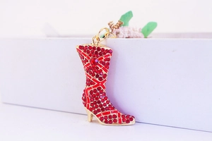 Macro detail of red rhinestone encrusted high heel boot pendant on a golden keychain