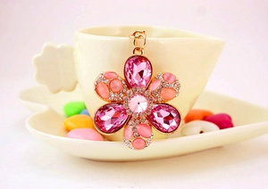 Detailed view of pink crystal flower keychain charm with gold plating on a cup