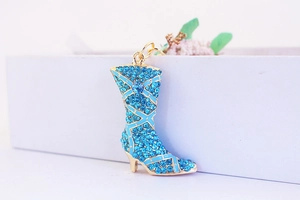 Detail of blue rhinestone studded boot keychain with gold-plated metal accents and hook
