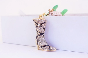 Detail of creative boot-shaped keychain with gold plating and white crystal rhinestones