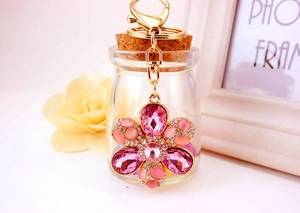 Macro shot of a floral keychain with pink rhinestones and opal stones on a gold clasp
