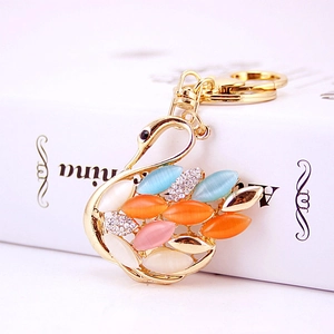Macro detail of golden swan keychain with multicolored cat eye stones and crystals