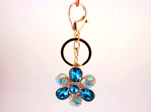 Close-up of golden flower keychain with blue crystals and cat eye stone petals