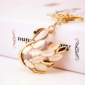 Close-up of golden swan keychain featuring white cat-eye stones and sparkling rhinestones