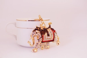 Detailed view of a rhinestone elephant keychain leaning on a white porcelain cup